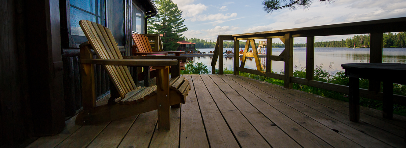 Two empty chairs on a deck at a lake house